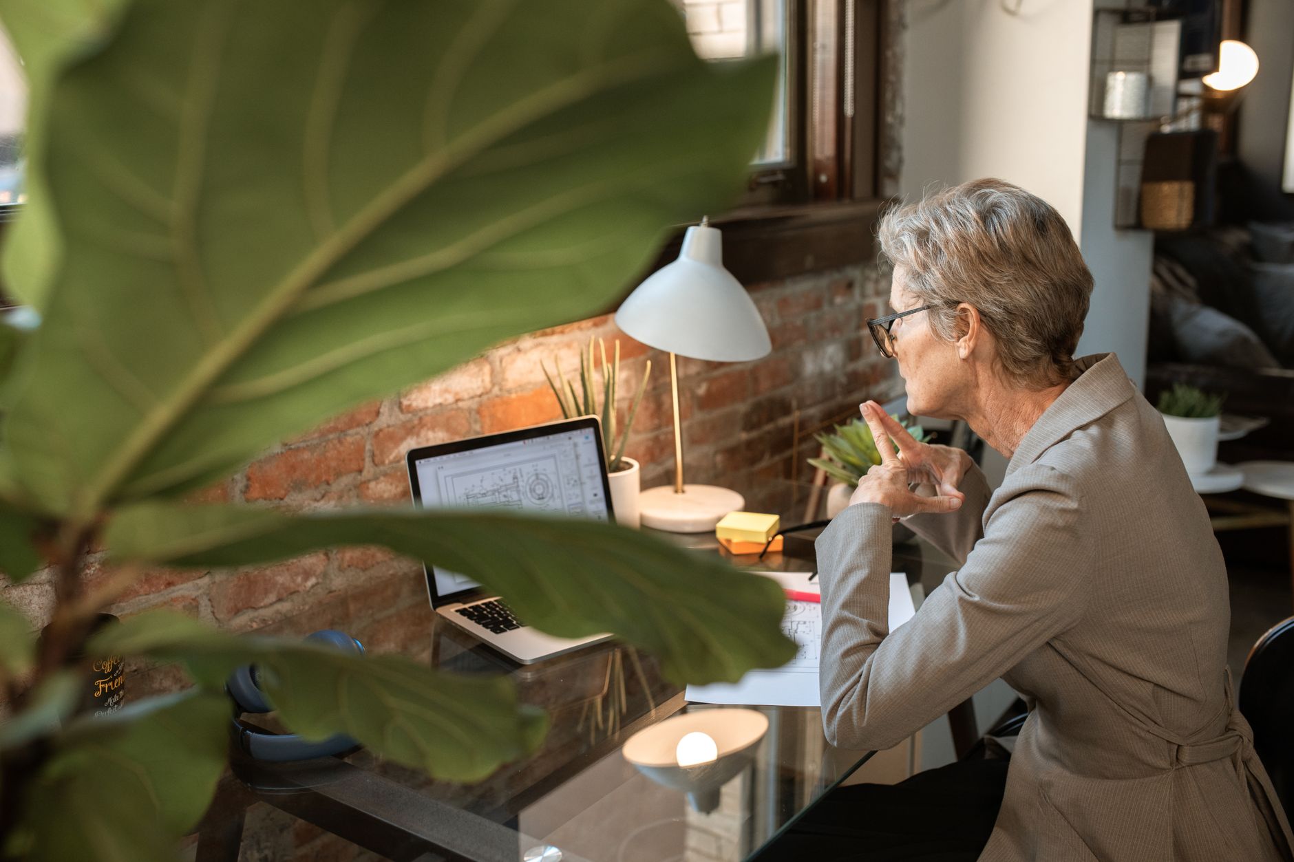A small-business owner works calmly at a laptop in a bright home office.