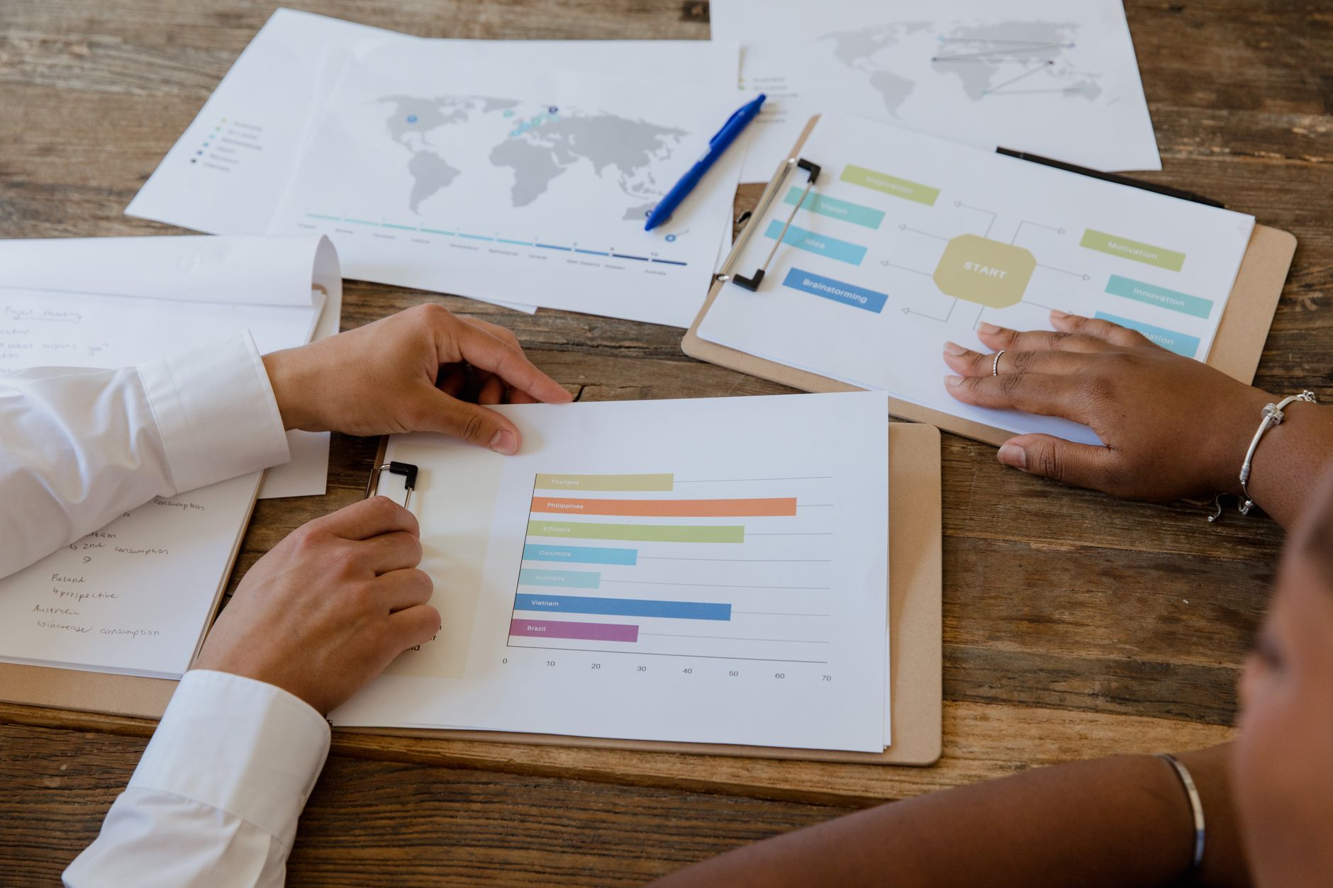 Colleagues review charts and reports spread across a meeting table.