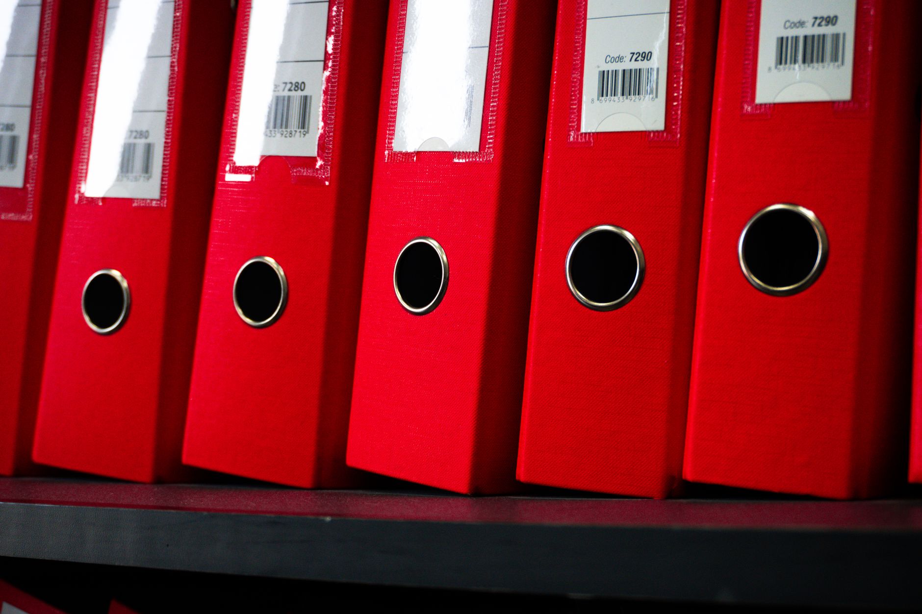 Close-up of red office binders neatly arranged on a shelf