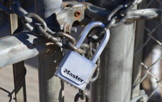 Close-up of a padlock securing a metal chain on a gate