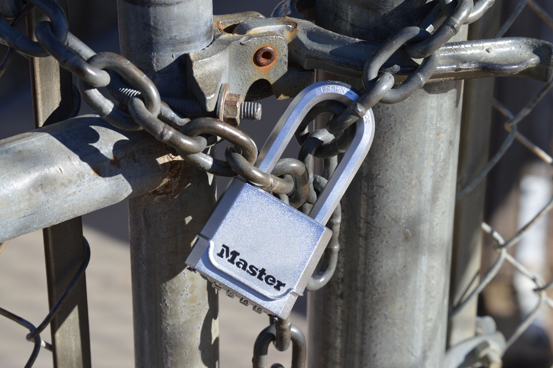 Close-up of a padlock securing a metal chain on a gate