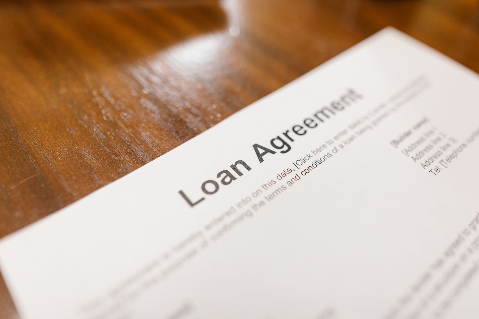 Close-up of a printed loan agreement document lying on a wooden table