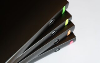 Stack of black office binders with colorful tabs on a table