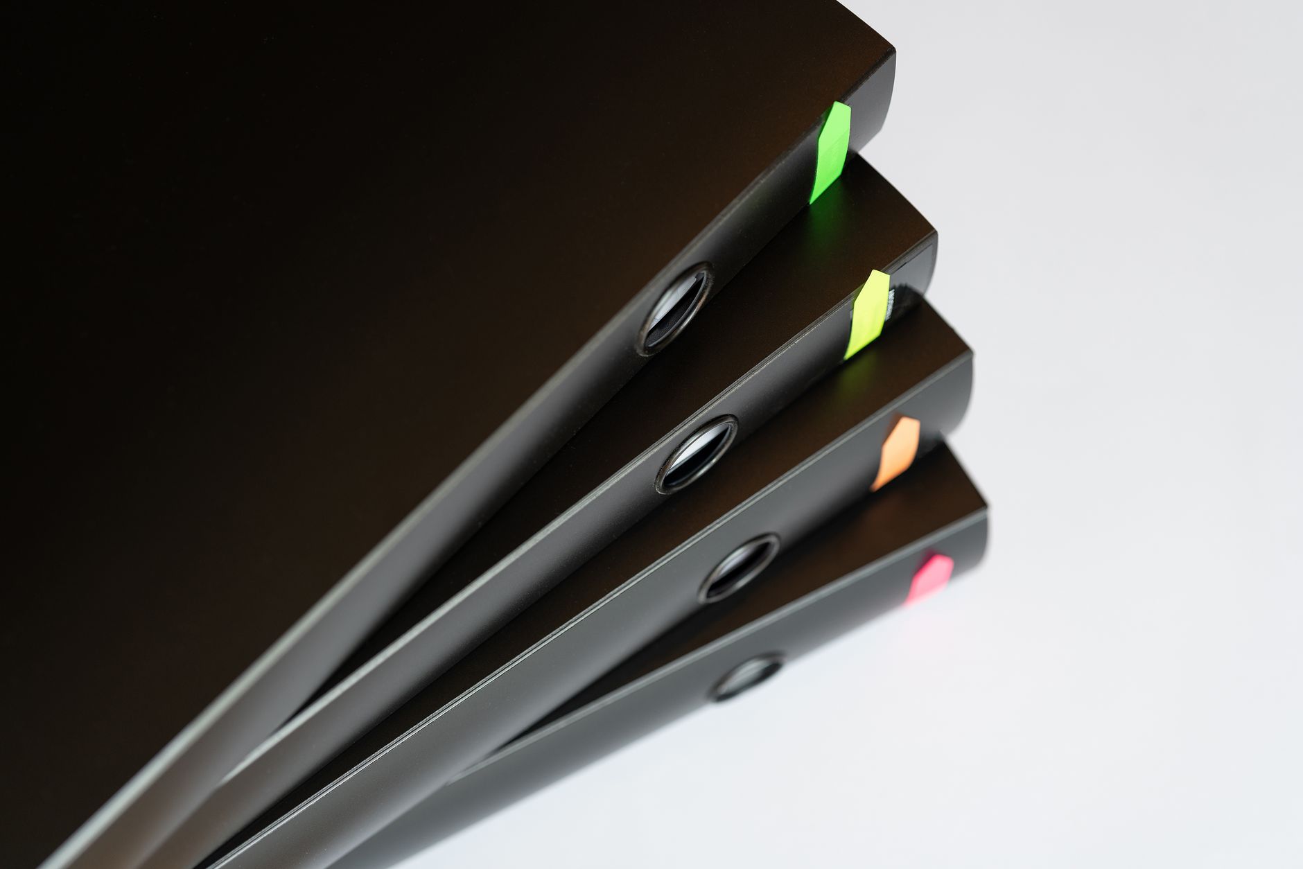Stack of black office binders with colorful tabs on a table