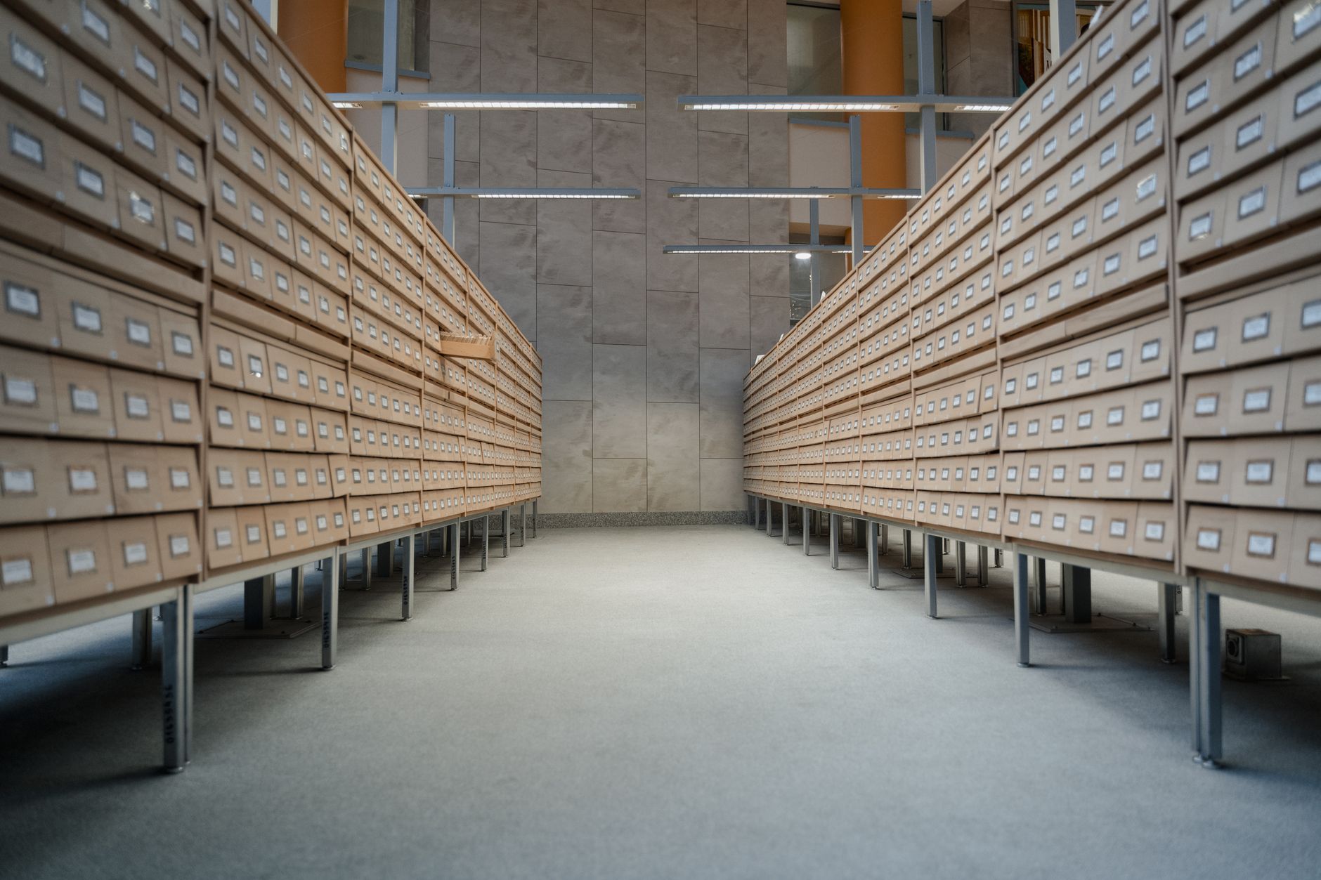 Rows of neatly labeled wooden drawers in a bright, organized archive room.