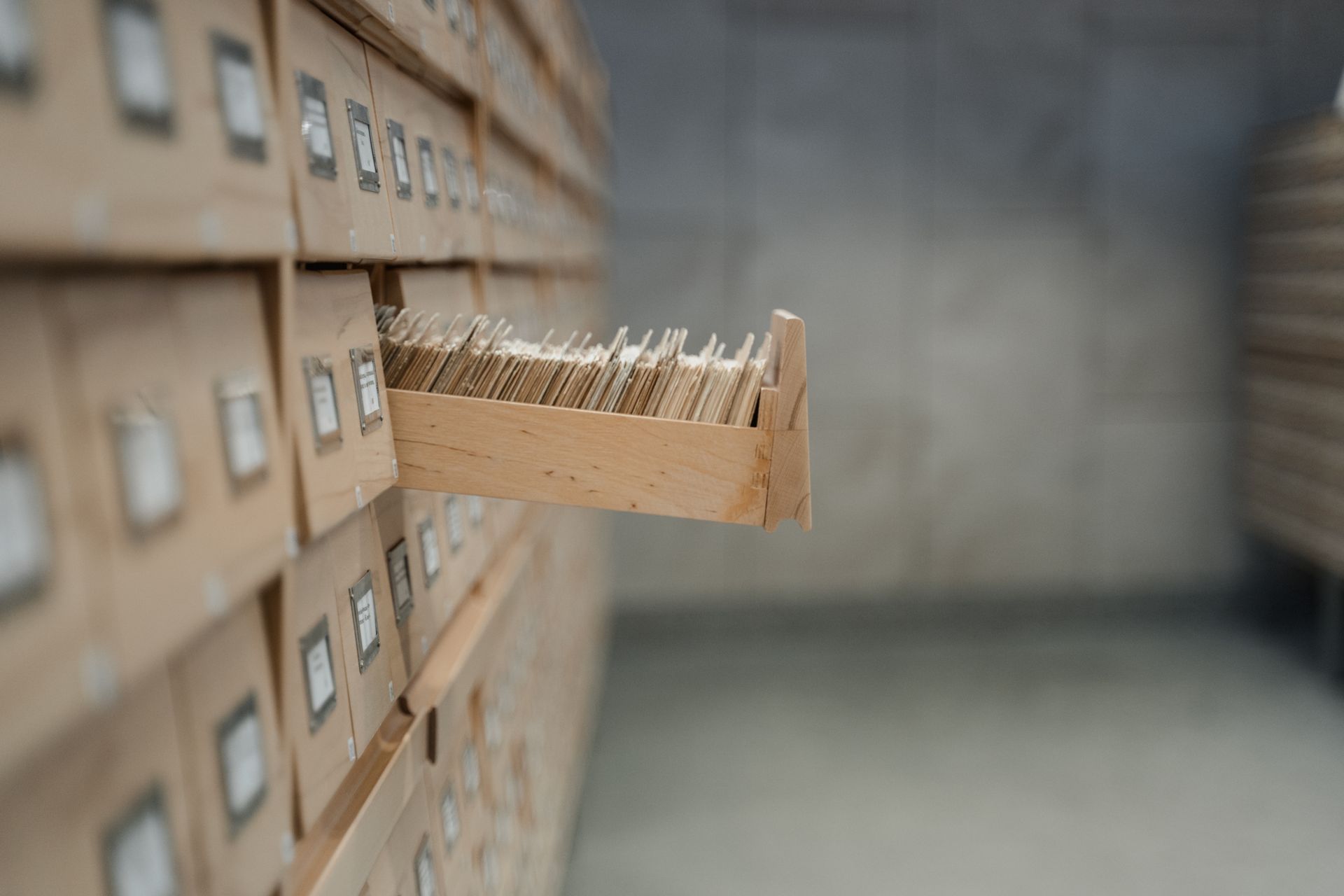 Open wooden card catalog drawer full of index cards in an archive